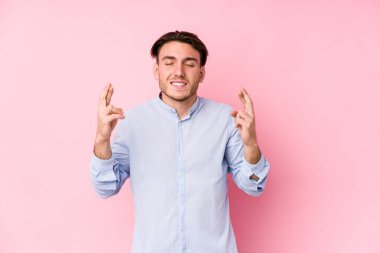 Pembe arka planda poz veren beyaz bir genç şans dilemek için şans diliyor.