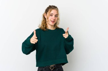 Beyaz arka plandaki genç beyaz kadın parmaklarıyla ön tarafı işaret ediyor..