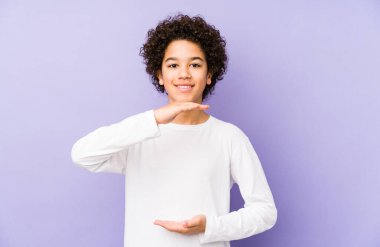 Afrikalı Amerikalı küçük çocuk iki eliyle bir şey tutuyor, ürün sunumu..