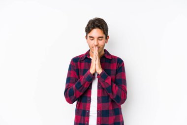 Pembe arka planda poz veren beyaz bir genç yalnız başına el ele tutuşup dua ediyor, kendinden emin hissediyor..