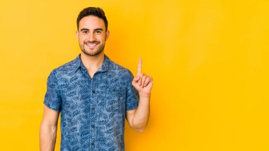Sarı fırında izole edilmiş genç beyaz bir adam bir numarayı parmağıyla gösteriyor..