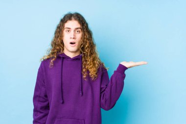 Uzun saçlı adam yalnız poz veriyor. Kopya alanını avucunun içinde tutmaktan etkilenmiş..