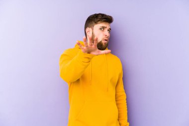 Mor arka planda izole genç bir adam yakın bir tehlike nedeniyle şoka uğruyor.