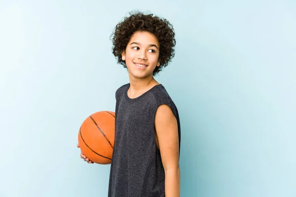 在蓝色背景下打篮球的小男孩看上去面带微笑 快乐而愉快 — 图库照片