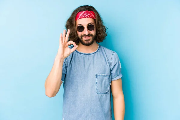 Young long hair man wearing a festival hipster look isolated cheerful and confident showing ok gesture.