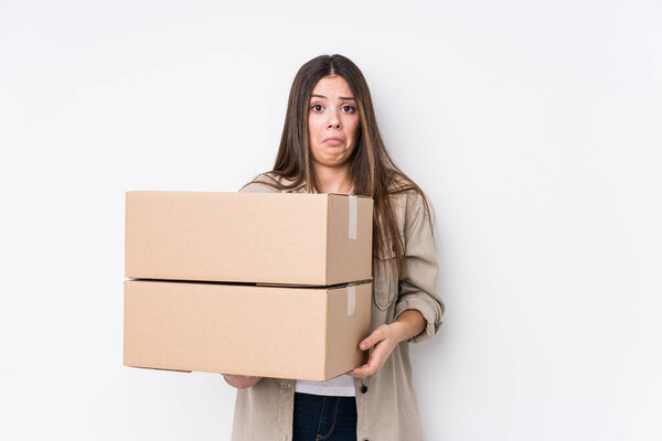 Young caucasian woman moving to a new home shrugs shoulders and open eyes confused.