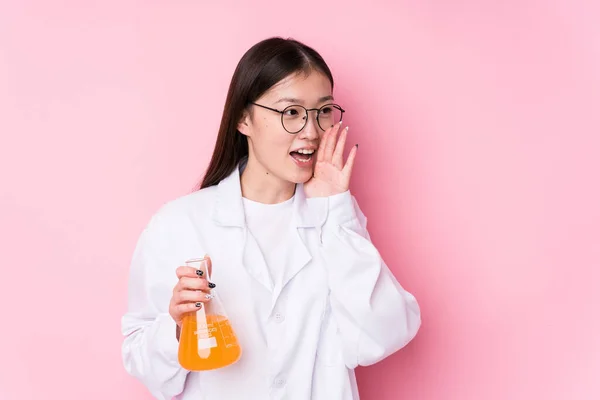 Young chinese scientific woman isolated shouting and holding palm near opened mouth.