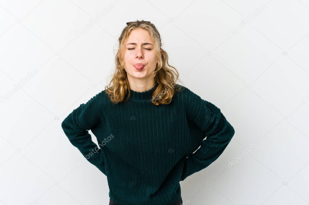 Young caucasian woman on white backrgound funny and friendly sticking out tongue.