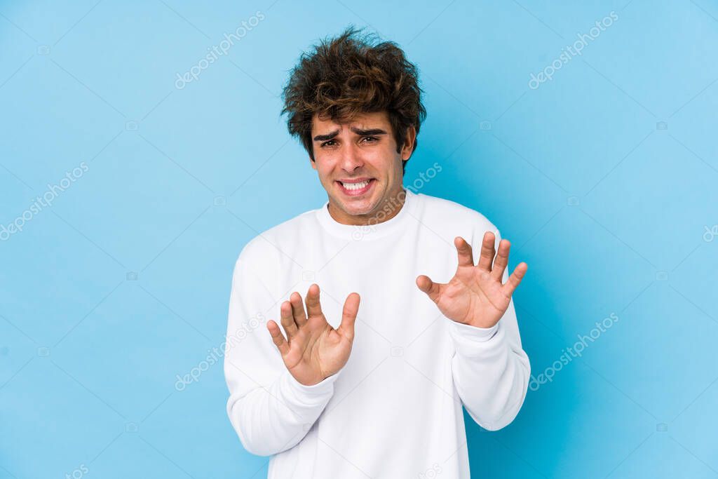 Young caucasian man against a blue background isolated rejecting someone showing a gesture of disgust.