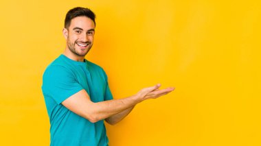 Kafkasyalı genç adam sarı fırında izole edilmiş. Elinde palmiye ağacının üzerinde bir kopyası var..