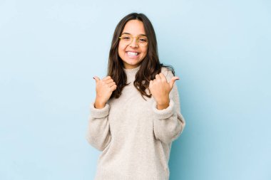 Latin kökenli genç bir kadın kendini soyutlamış. İki parmağını da kaldırmış, gülümsüyor ve kendinden emin..