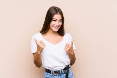 Kafkasyalı genç bir kadın yalnız poz veriyor. Baş parmağını kaldırıyor, gülümsüyor ve kendinden emin..