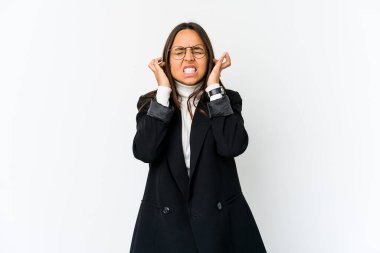 Genç melez iş kadını, beyaz arka planda izole edilmiş kulakları parmaklarıyla kaplayan, gürültülü bir ortam yüzünden stresli ve çaresiz..