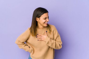 Mor arka planda soyutlanmış genç bir kadın gülüyor, elleri kalbimde, mutluluk kavramında..