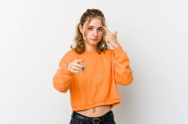 Beyaz arka planda beyaz tenli genç bir kadın parmağıyla tapınağı işaret ediyor, düşünüyor ve bir göreve odaklanıyor..