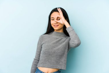 Genç Çinli bir kadın mavi arka planda izole edilmiş. Heyecanlı..