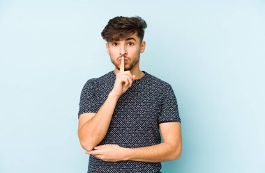 Mavi arka planda izole edilmiş genç bir Arap ya sır saklıyor ya da sessizlik istiyor..