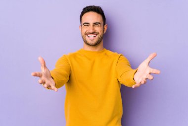 Mor arka planda izole genç beyaz adam kameraya sarıldığı için kendinden emin hissediyor..