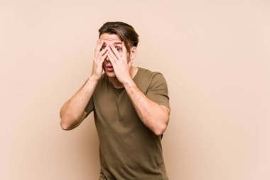 Kafkasyalı genç adam yalnız poz veriyor. Korkmuş ve gergin parmaklarıyla göz kırp..