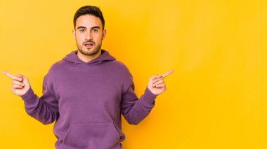 Sarı fırında izole edilmiş genç beyaz adam farklı kopya alanlarını gösteriyor, birini seçiyor, parmaklarıyla gösteriyor..