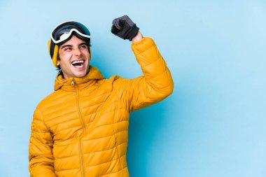 Kar kayağı gözlükleri takan genç kayakçı zafer kazandıktan sonra yumruğunu kaldırdı..