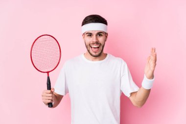 Badminton oynayan beyaz bir genç hoş bir sürprizle karşılaşıyor, heyecanlı ve el kaldırıyor..
