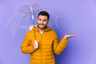 Elinde şemsiye tutan genç yakışıklı bir adam avucundaki fotokopi alanını gösteriyor ve belinde başka bir el tutuyor..