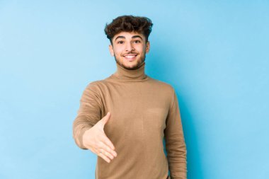 Genç Arap adam kameraya elini uzatarak selam veriyor..