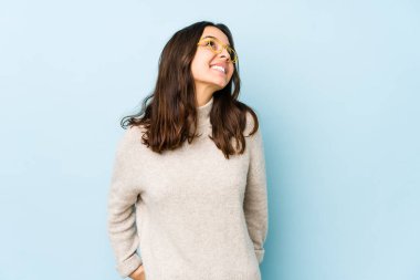 Latin kökenli genç bir kadın izole edilmiş, rahat ve mutlu bir şekilde gülüyor, boynunda dişlerini gösteriyor..