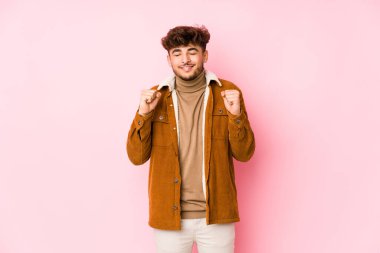 Pembe arka planda yalnız poz veren genç bir Arap.