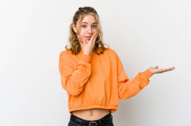 Beyaz arka planda oturan beyaz tenli genç bir kadın avucunun içinde fotokopi alanı tutuyor, el üstünde tutuyor. Şaşırmış ve mutlu..