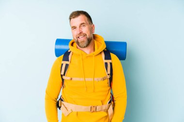 Kıdemli yürüyüşçü mavi arka planda izole edilmiş mutlu, güler yüzlü ve neşeli.