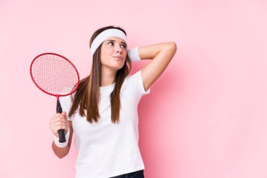 Badminton oynayan beyaz bir kadın başının arkasına dokunuyor, düşünüyor ve bir seçim yapıyor..