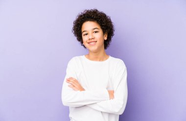 Kendini güvende hisseden, kararlılıkla kollarını kavuşturan Afrikalı Amerikalı küçük çocuk..