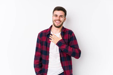 Beyaz arka planda poz veren beyaz tenli genç adam kahkahalar atıyor..