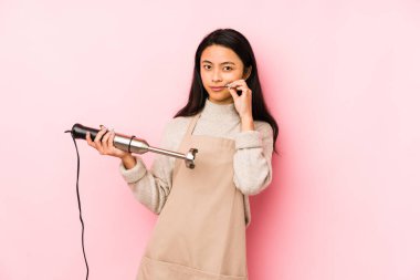 Karıştırıcı tutan genç Çinli kadın omuz silker ve gözleri açık kalır..