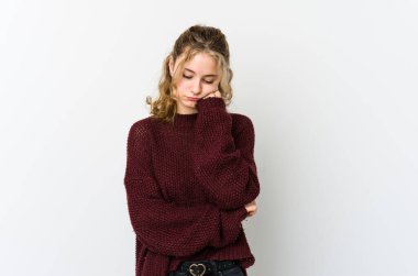 Beyaz arka planda oturan, üzgün ve dalgın hisseden, kopyalama alanına bakan genç beyaz bir kadın..