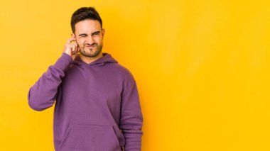 Kafkasyalı genç adam sarı fırında izole edilmiş parmaklarıyla kulaklarını kapatıyor, gürültülü bir ortam yüzünden stresli ve çaresiz..