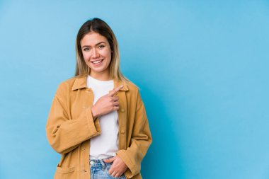 Beyaz bir kadın gülümsüyor ve boş alanda bir şeyler gösteriyor..