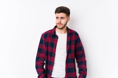 Beyaz arka planda poz veren beyaz bir genç kafası karışmış, şüpheli ve güvensiz hissediyor..