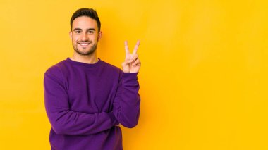 Sarı fırında izole edilmiş genç beyaz adam iki numarayı parmaklarıyla gösteriyor..