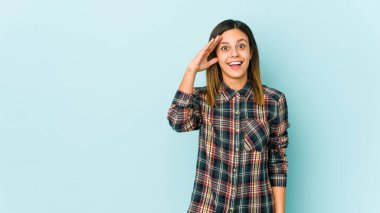 Mavi arka planda izole edilmiş genç bir kadın yüksek sesle bağırıyor, gözleri açık ve elleri gergin tutuyor..