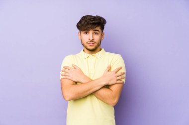 Mor arka planda izole edilmiş genç bir Arap adam düşük sıcaklık ya da hastalık nedeniyle soğuyor..