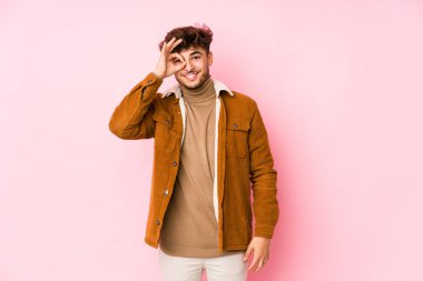 Pembe arka planda yalnız poz veren genç bir Arap.