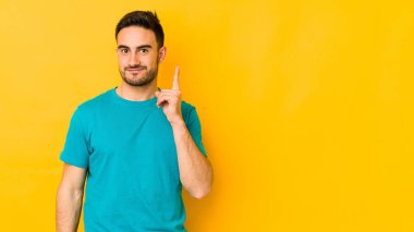Sarı fırında izole edilmiş genç beyaz bir adam bir numarayı parmağıyla gösteriyor..