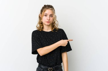 Beyaz arka planda genç beyaz bir kadın gülümsüyor ve boş uzayda bir şeyler gösteriyor..