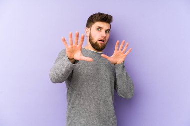 Mor arka planda izole genç beyaz adam yakın bir tehlike nedeniyle şoka uğruyor