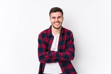 Beyaz arka planda poz veren beyaz bir genç adam yalnız gülüyor ve eğleniyor..