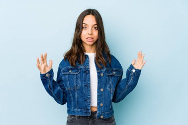 Genç, Latin kökenli bir kadın, kendini izole etmiş, parmaklarıyla küçük bir şey tutuyor, gülümsüyor ve kendinden emin..