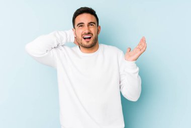 Mavi arka planda izole edilmiş genç beyaz adam öfkeyle bağırıyor..